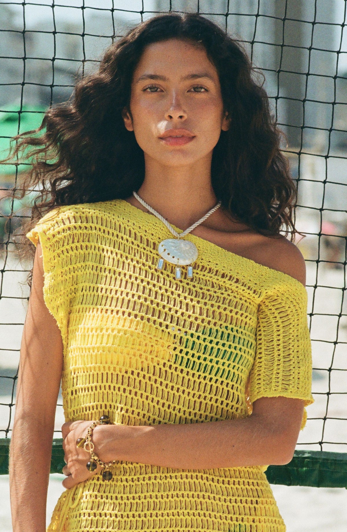 White beaded choker necklace worn close to the neck with a rectangular shell-like pendant.
