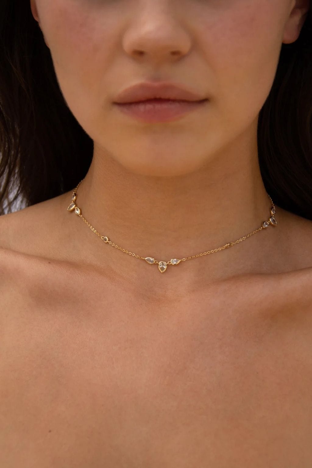 Gold-tone choker necklace with teardrop-shaped crystal accents spaced along delicate chain.