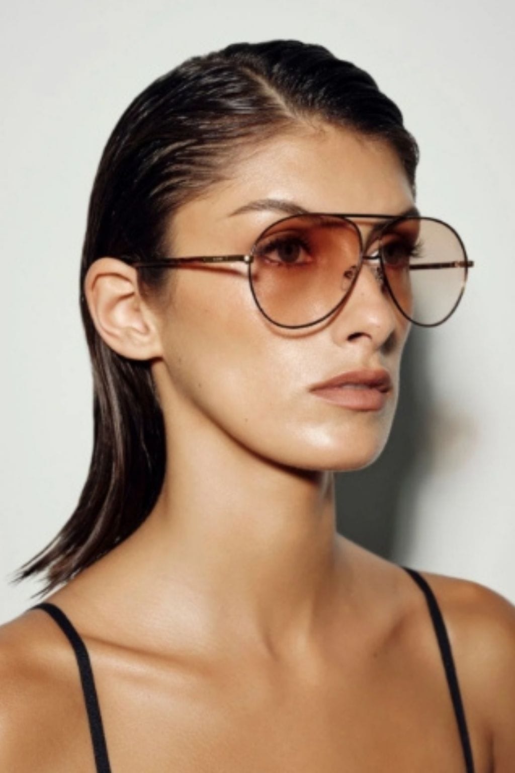 Woman wearing tortoiseshell aviator sunglasses with gradient brown lenses and metal frame.