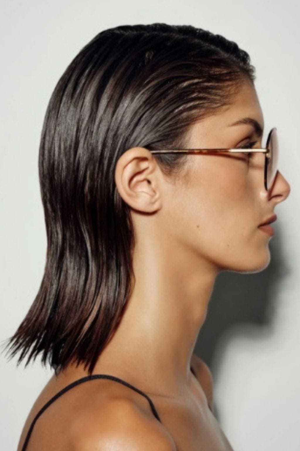 Tortoiseshell and beige eyeglasses with metal arms worn by a person in profile view.