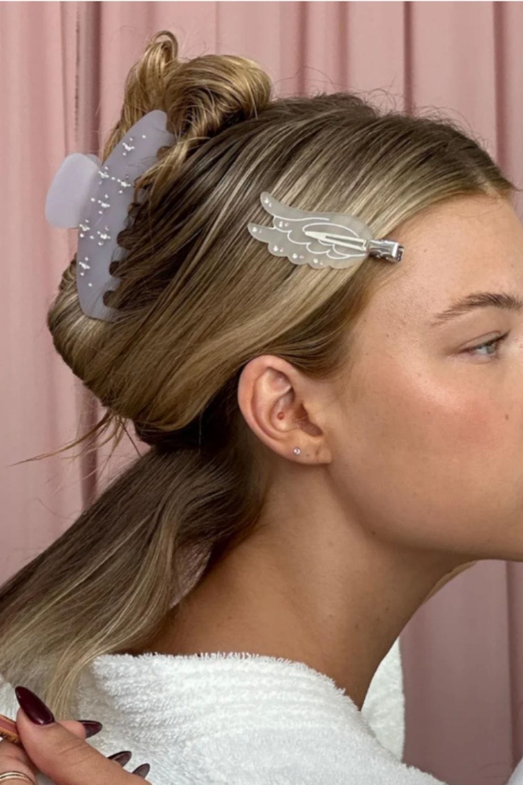 Two large hair clips with wing design and textured finish worn in styled hair.