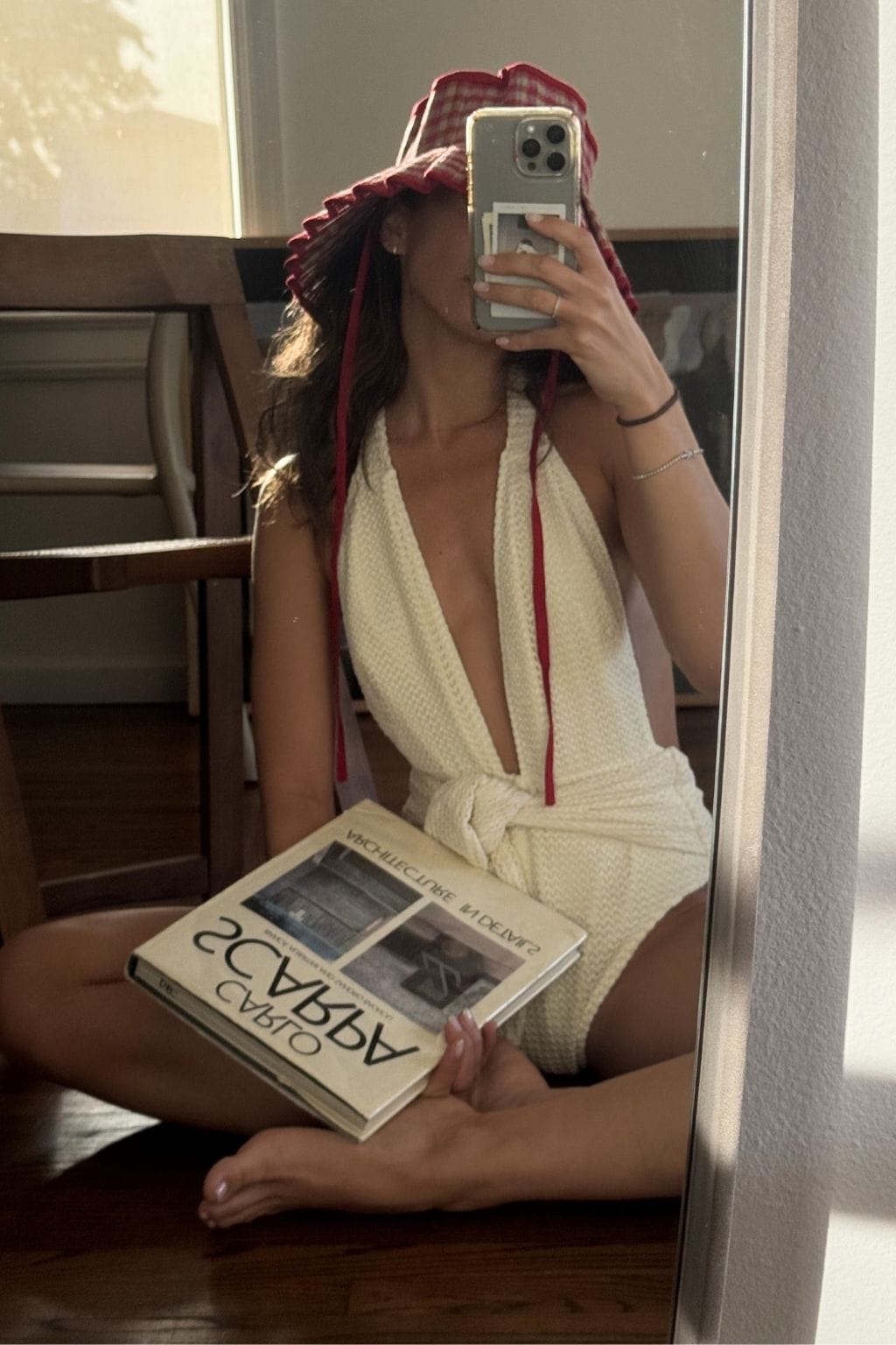 Cream halter tie-up one-piece swimsuit with textured fabric and burgundy tie straps, worn in mirror selfie.
