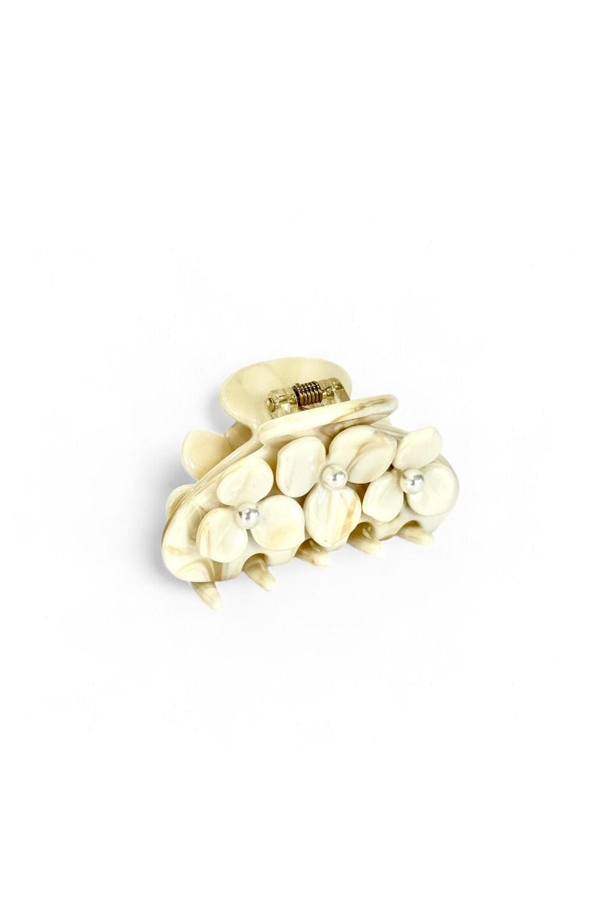 Cream-colored claw hair clip with marble texture and pearl bead accents, metal spring closure.