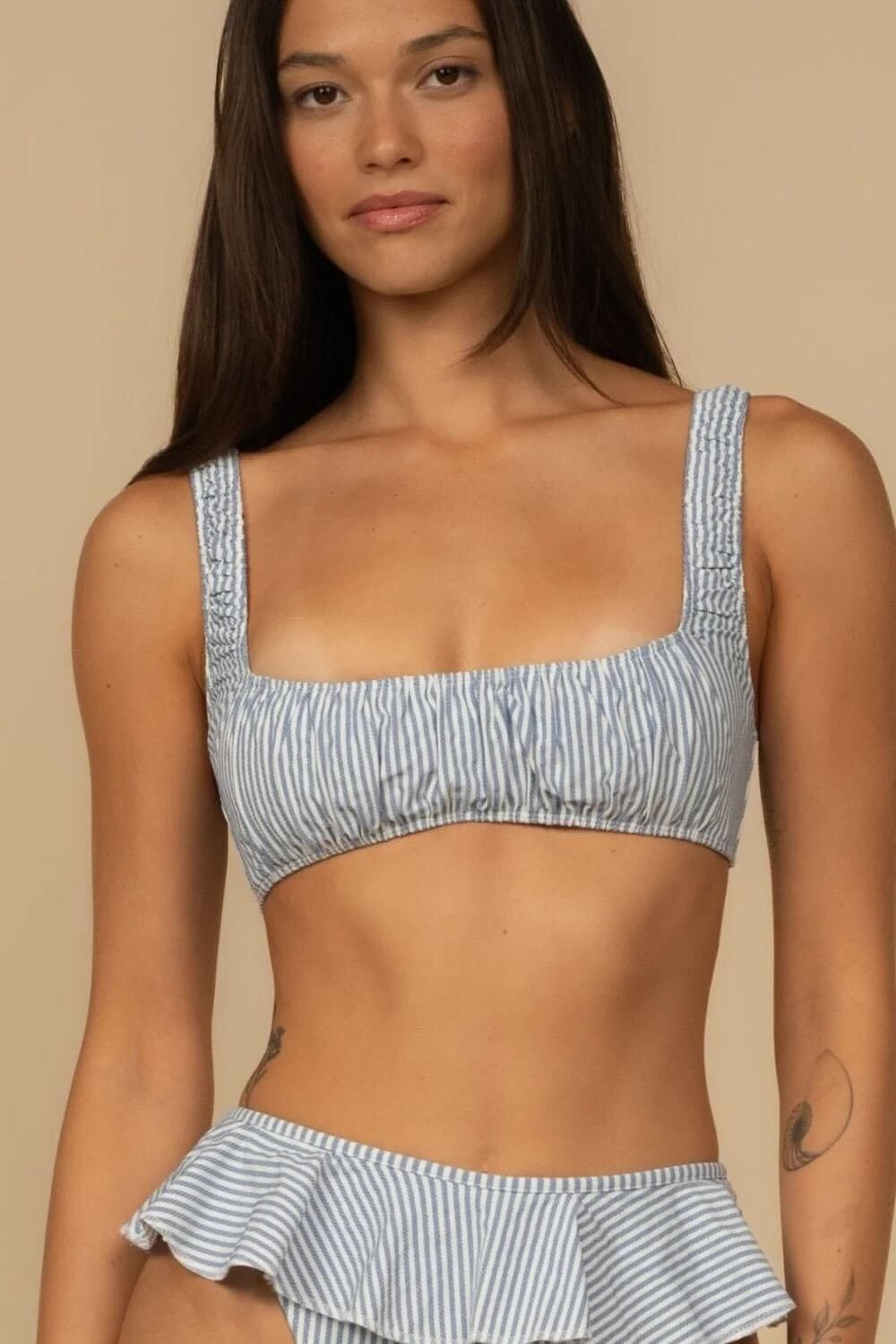 Blue and white striped bikini top with square neckline and wide shoulder straps on model.