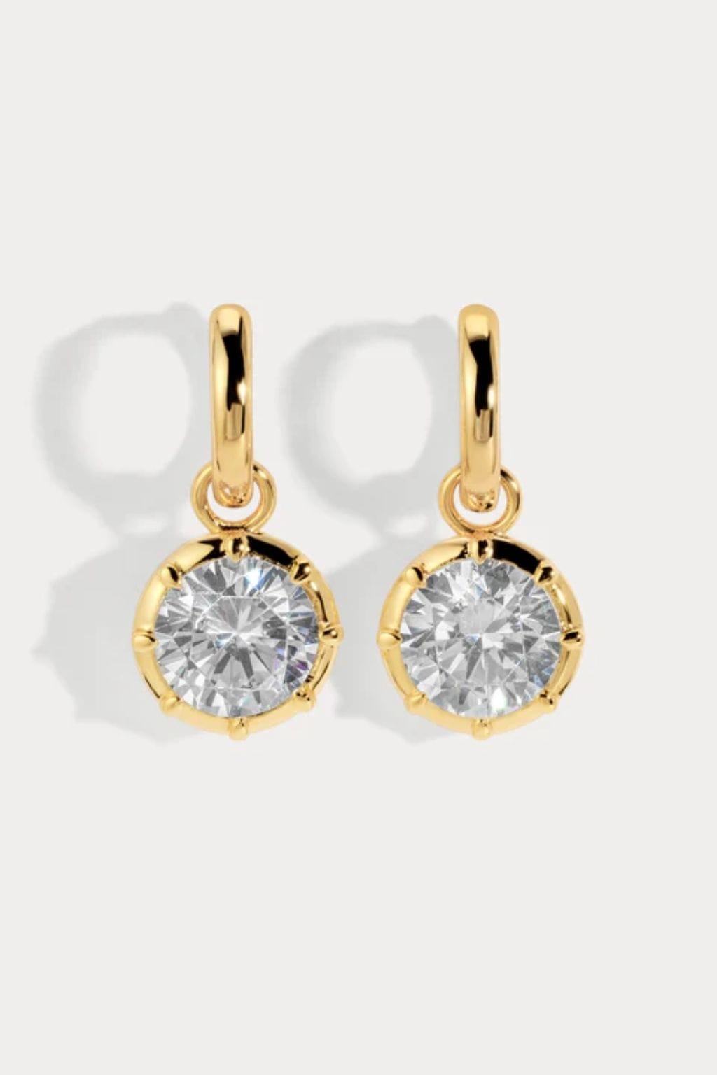 Pair of gold-toned hoop earrings with round clear crystal pendant drops.
