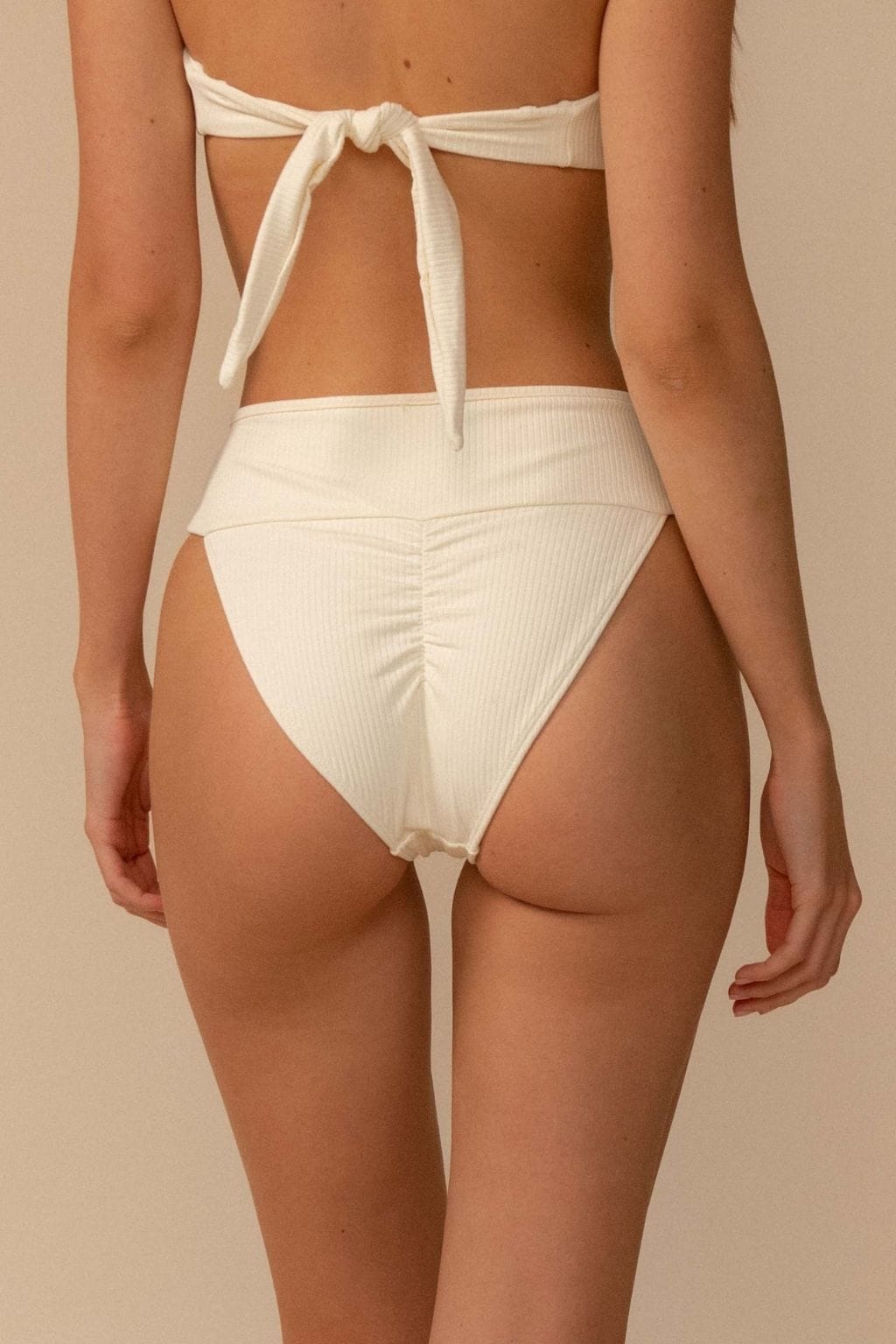 Cream ribbed bikini bottom with high-waisted fit and tie-side closure detail.