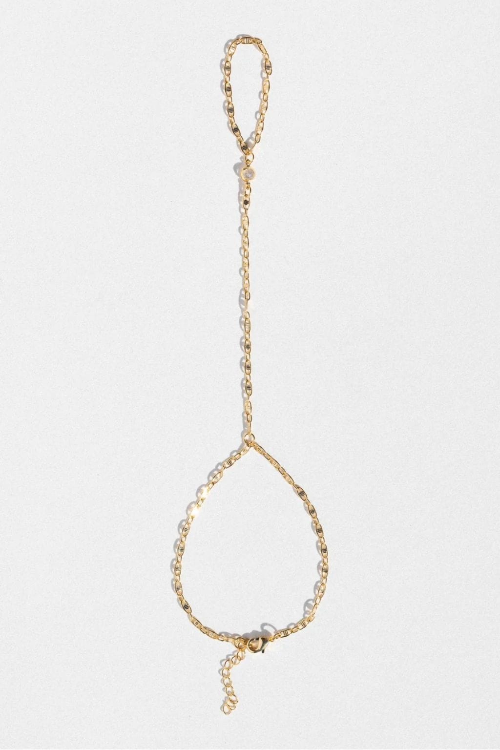 Gold-toned hand chain with linked chain design and teardrop-shaped loop at bottom.