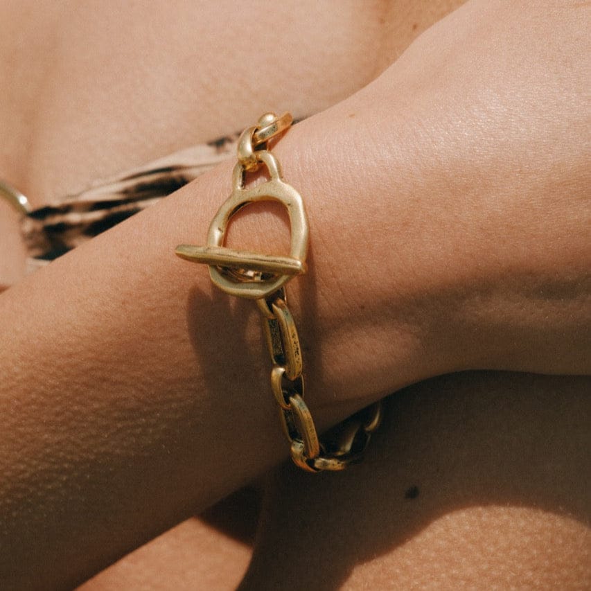 Gold-toned chain bracelet with toggle clasp, worn on wrist.