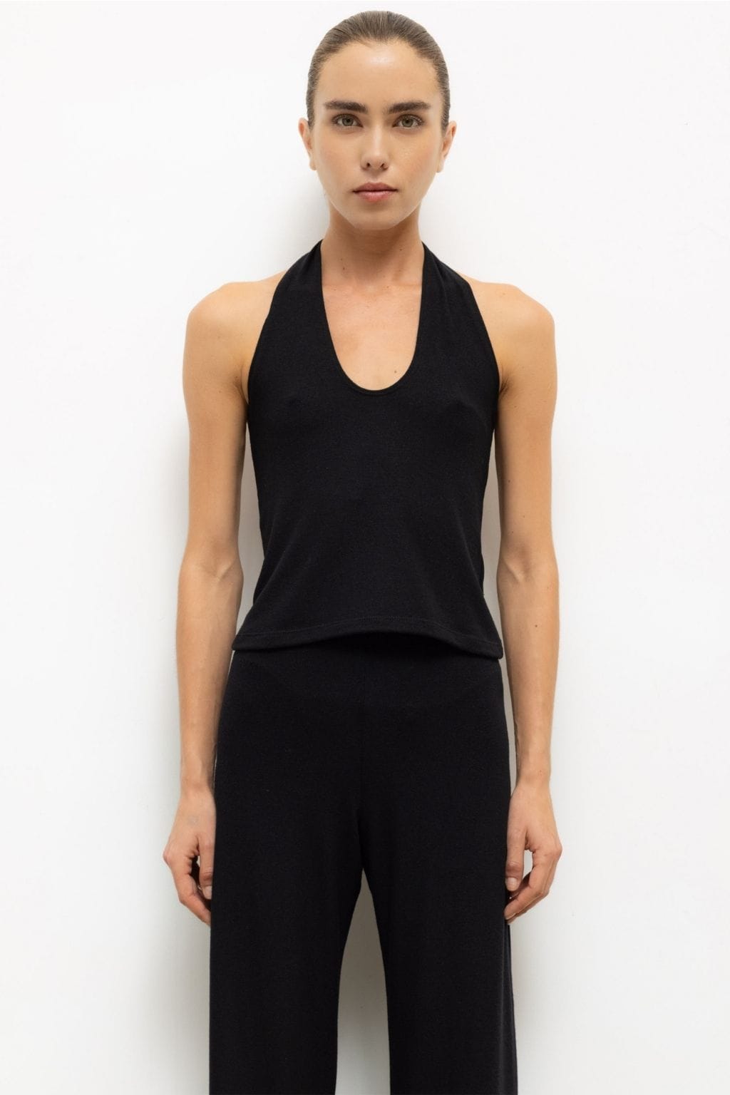 Black halter top with scoop neckline worn with matching black pants.