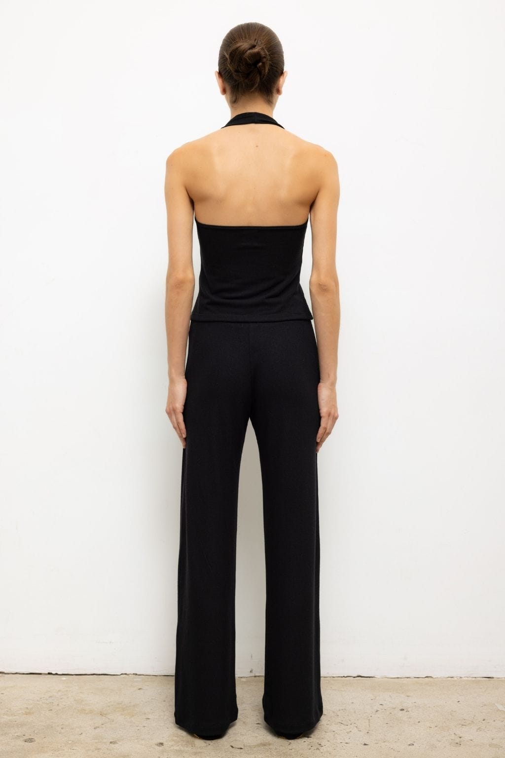 Black wide-leg pants with halter neckline top, rear view on model.