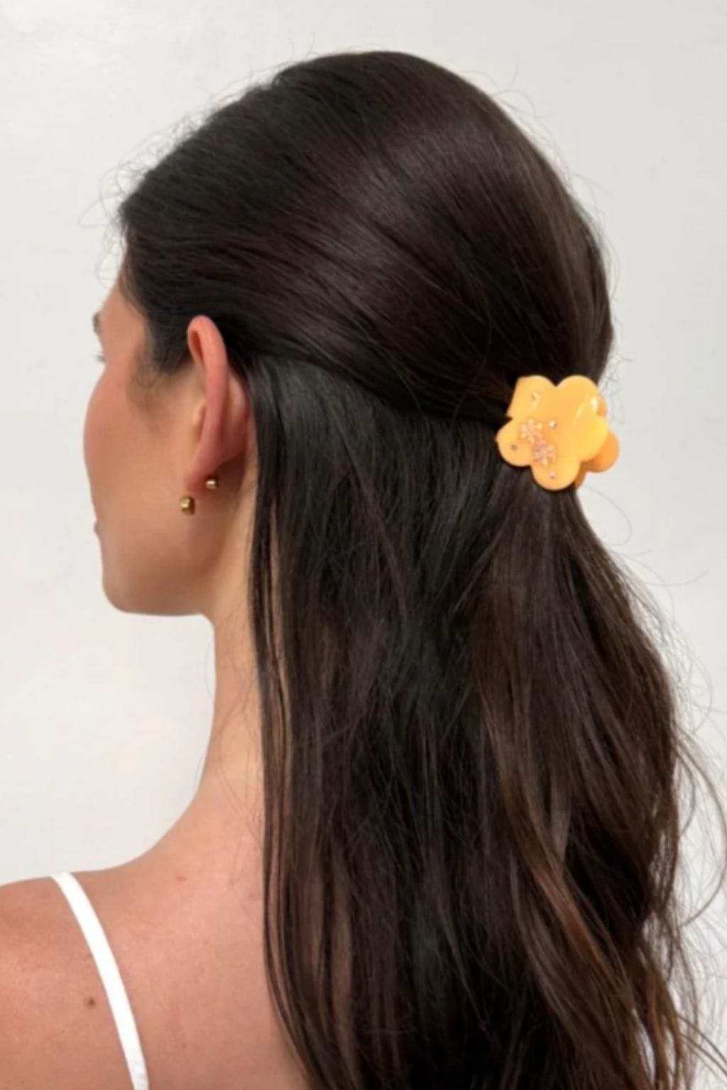 Peach-colored flower-shaped hair clip clipped into dark hair on the side of a person's head.