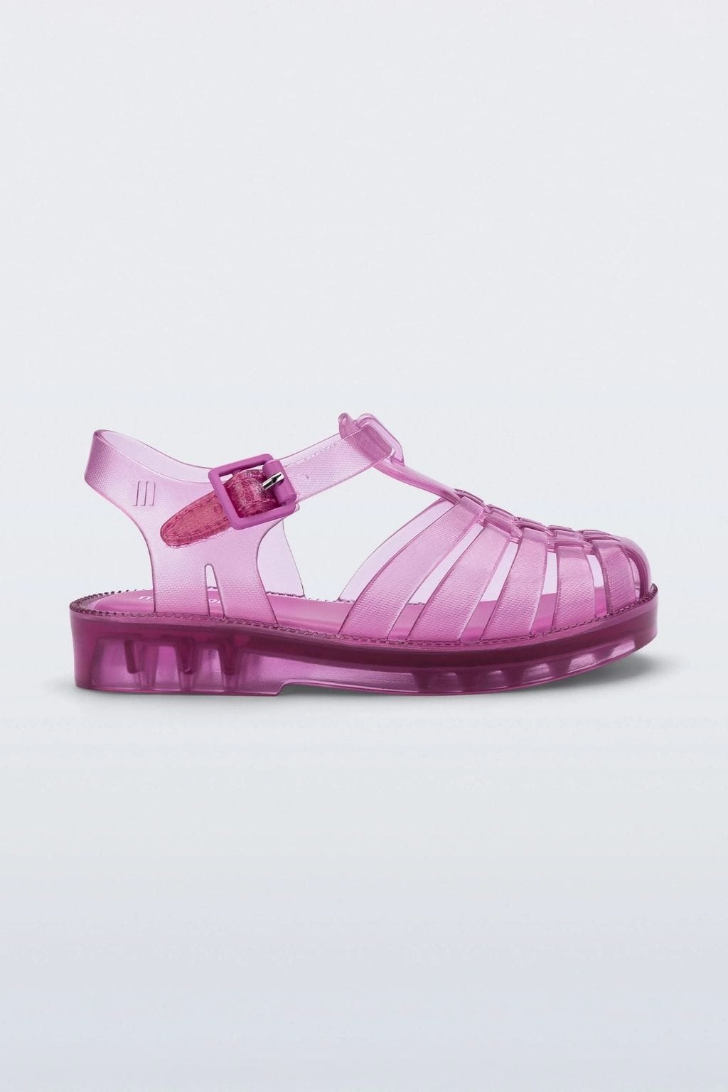Transparent pink jelly sandal with buckled ankle strap and ribbed sole, shown in side profile.