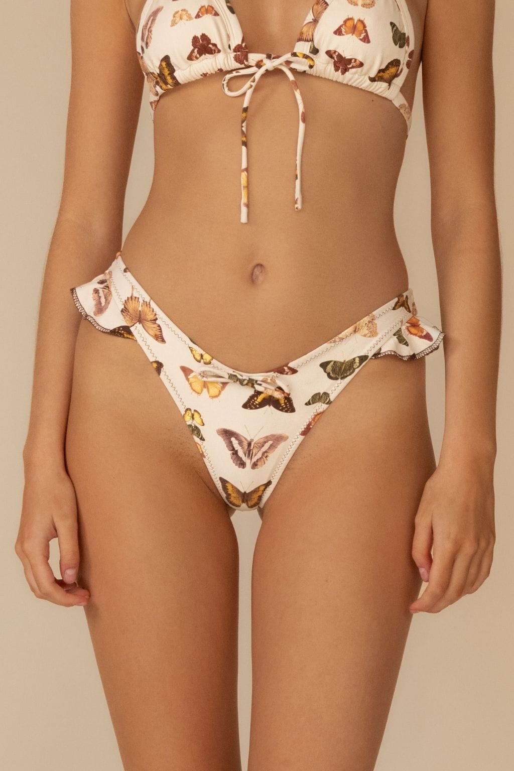 Cream bikini bottom with multicolored butterfly print and ruffled edges on leg openings.