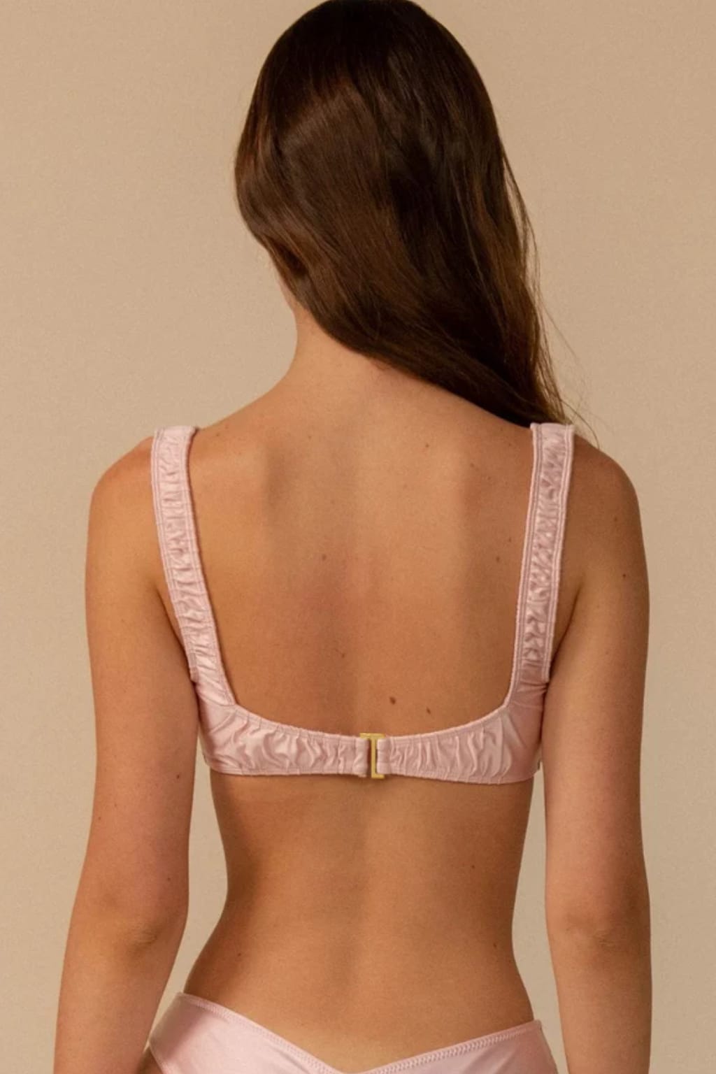 Pale blush bikini top with textured fabric, square neckline, and gold back clasp shown from rear view.