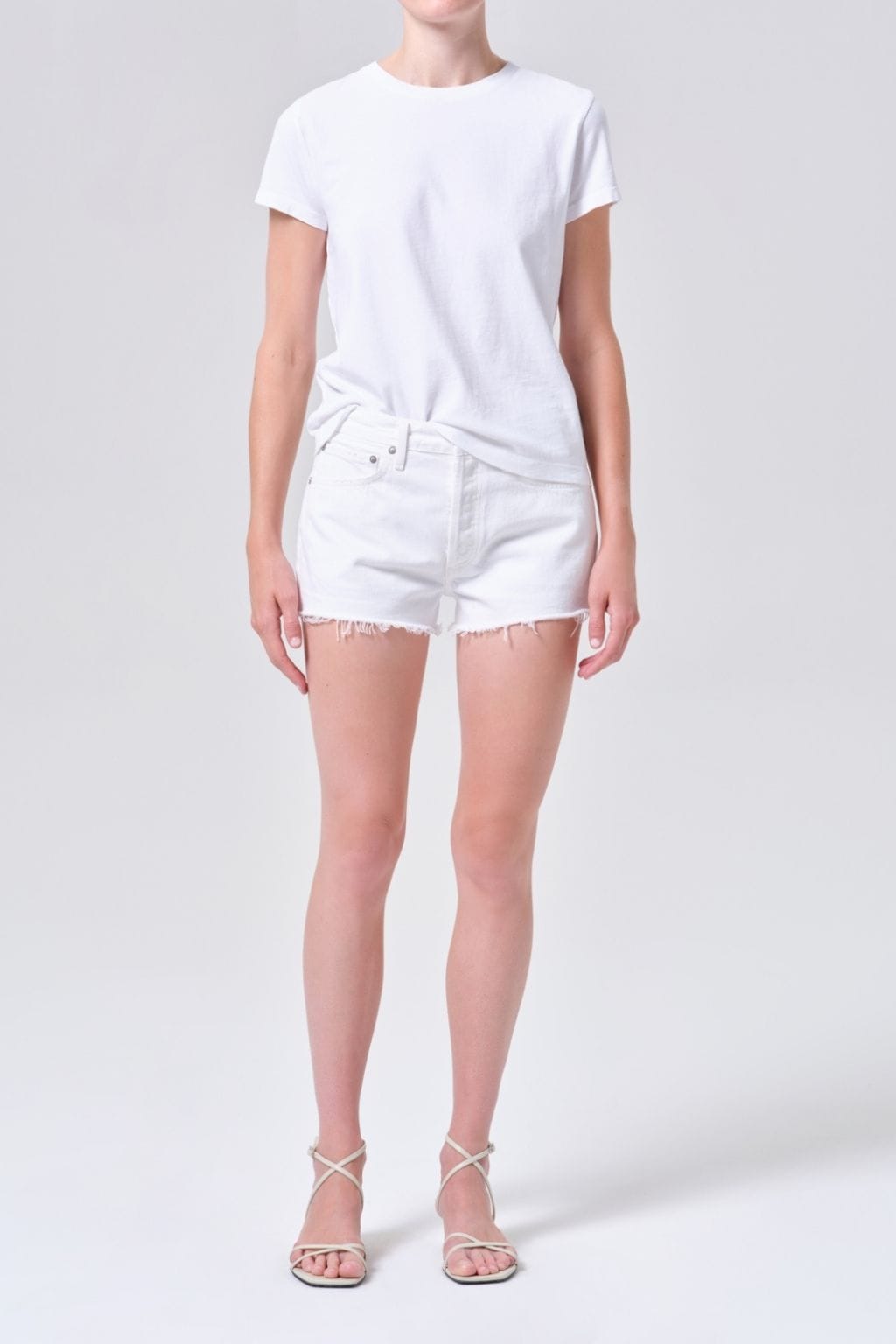 White short-sleeve t-shirt and white denim shorts with distressed thighs on model.
