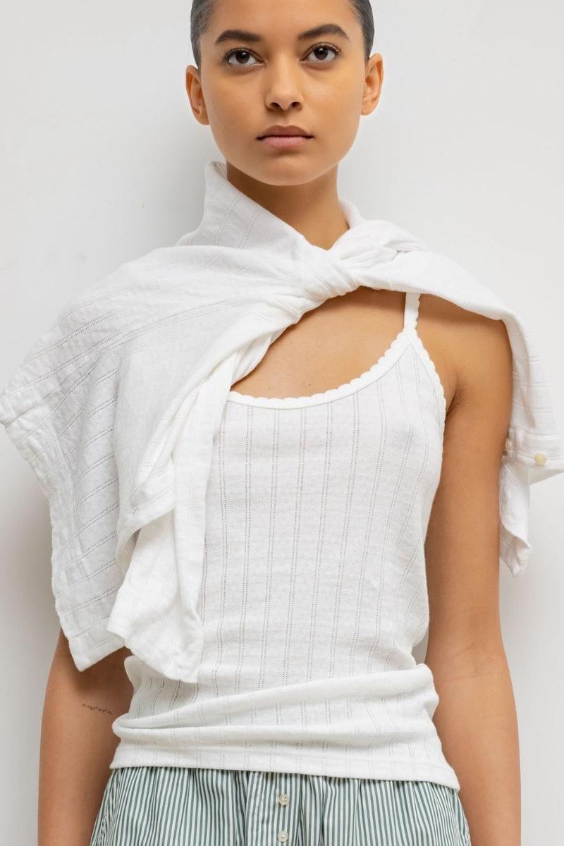 White pointelle tank top with vertical ribbed texture and rounded neckline, worn with a matching white shawl.