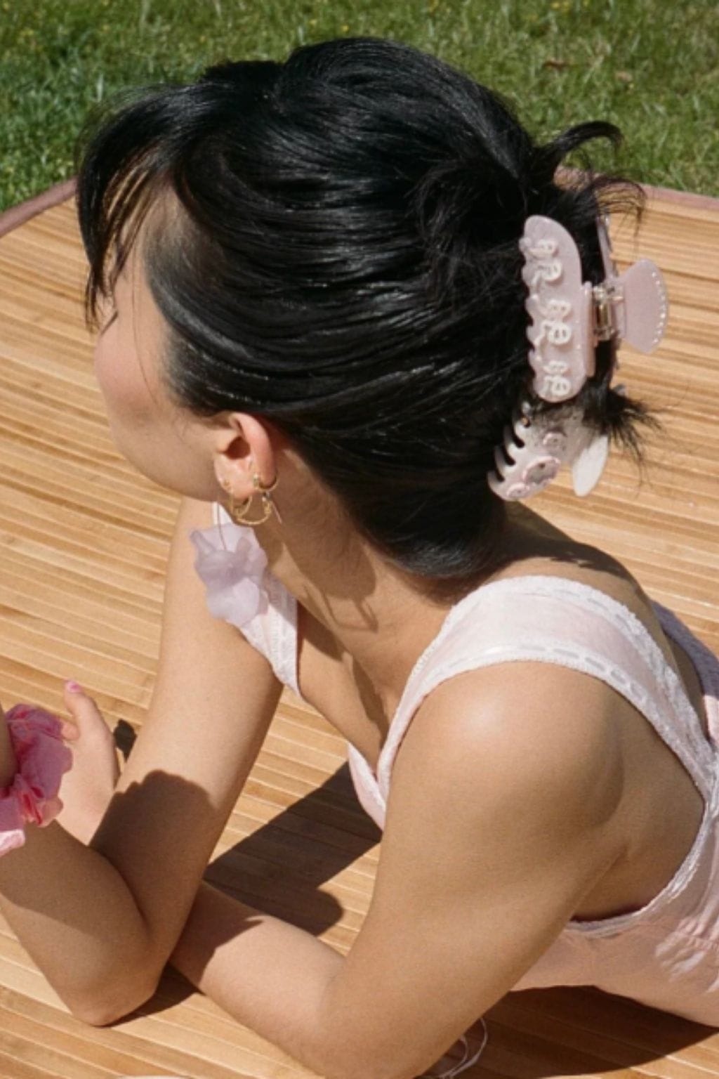 Pink and white decorative hair clip with scalloped edges worn in an updo hairstyle.
