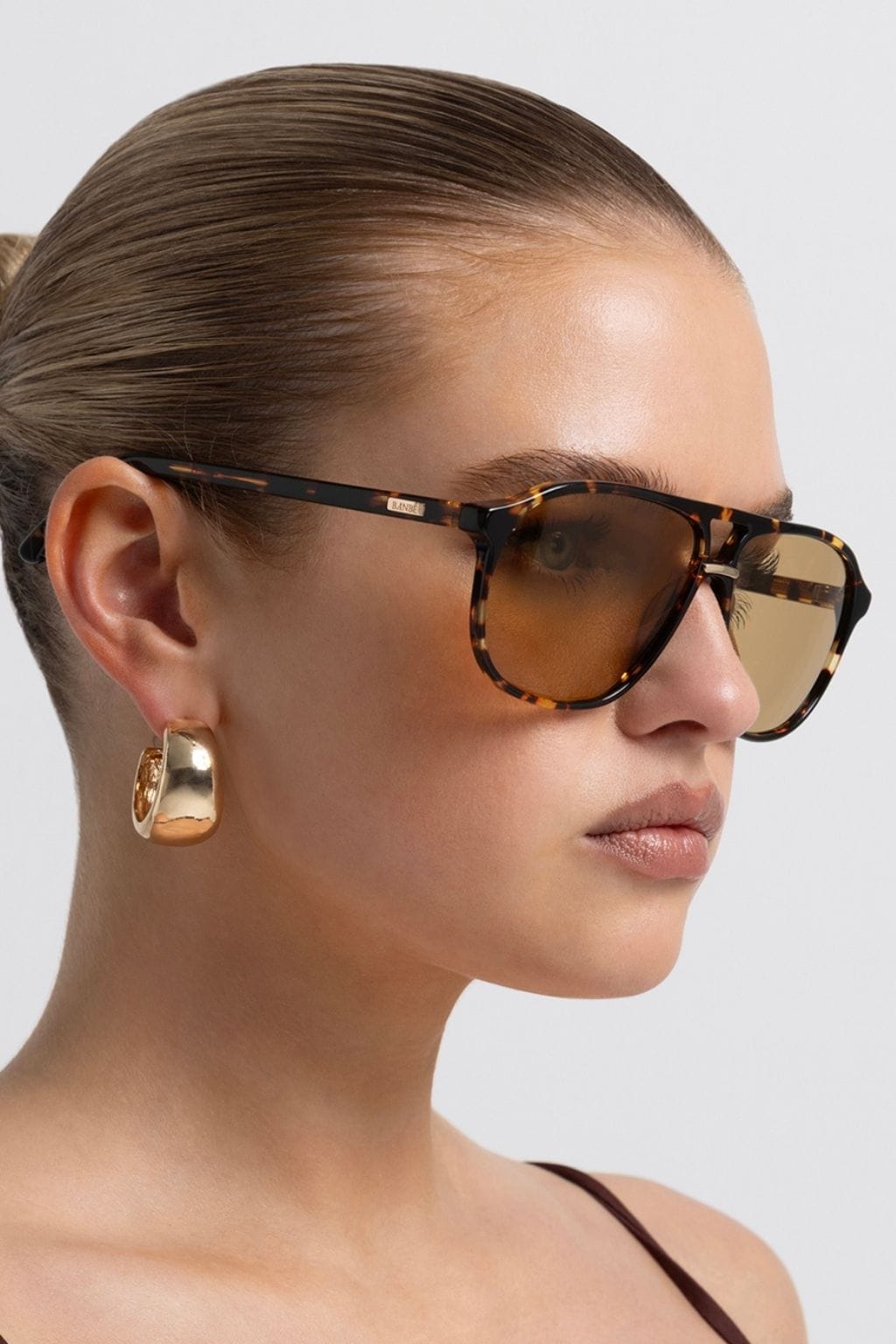 Amber tortoise acetate sunglasses with yellow-tinted lenses and black temples worn on a model's face.