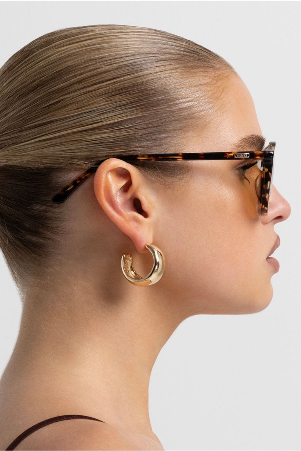 Amber tortoise rectangular eyeglasses worn by a person in profile view.