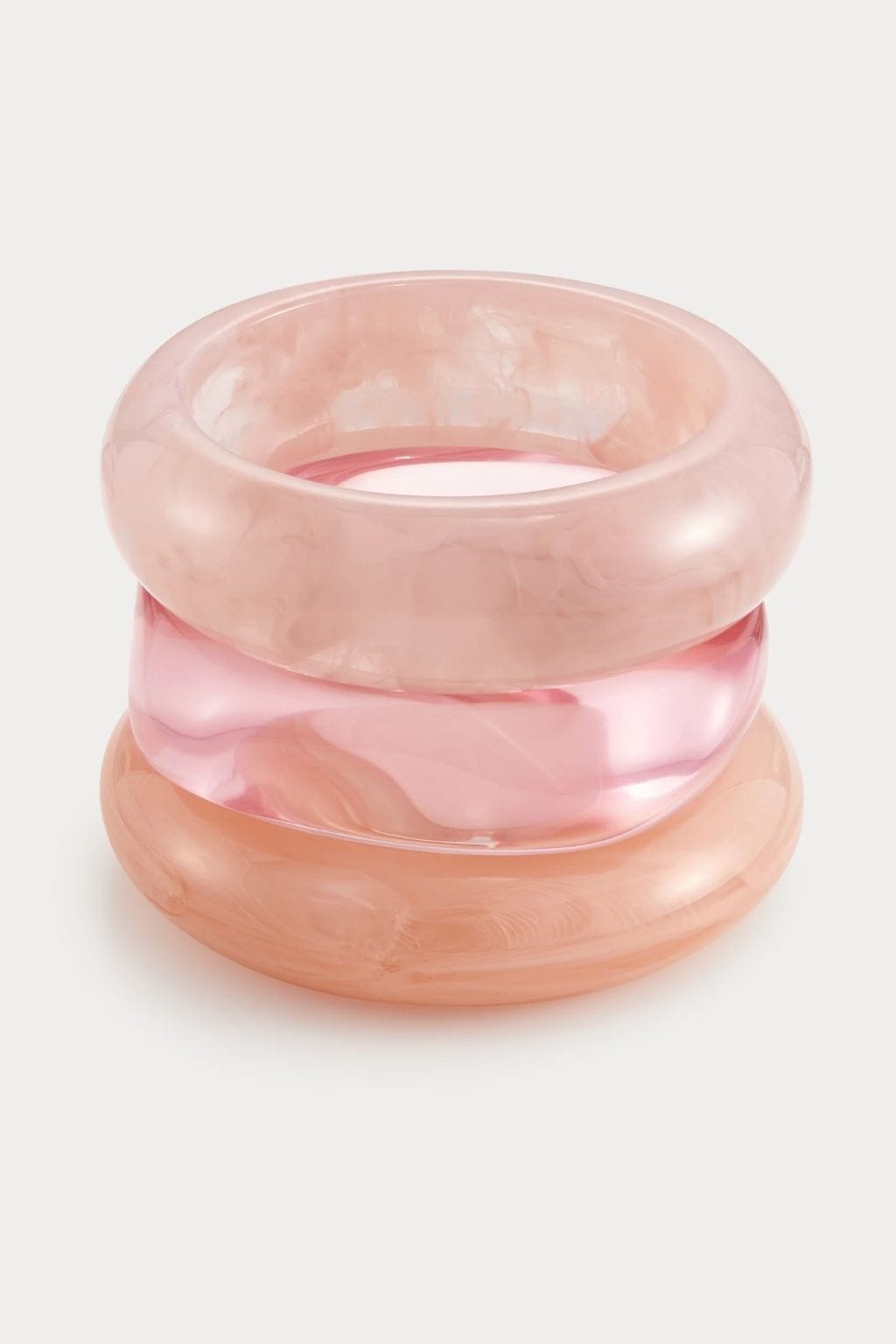 Three stacked pink resin bangles in varying shades, displayed against a light background.