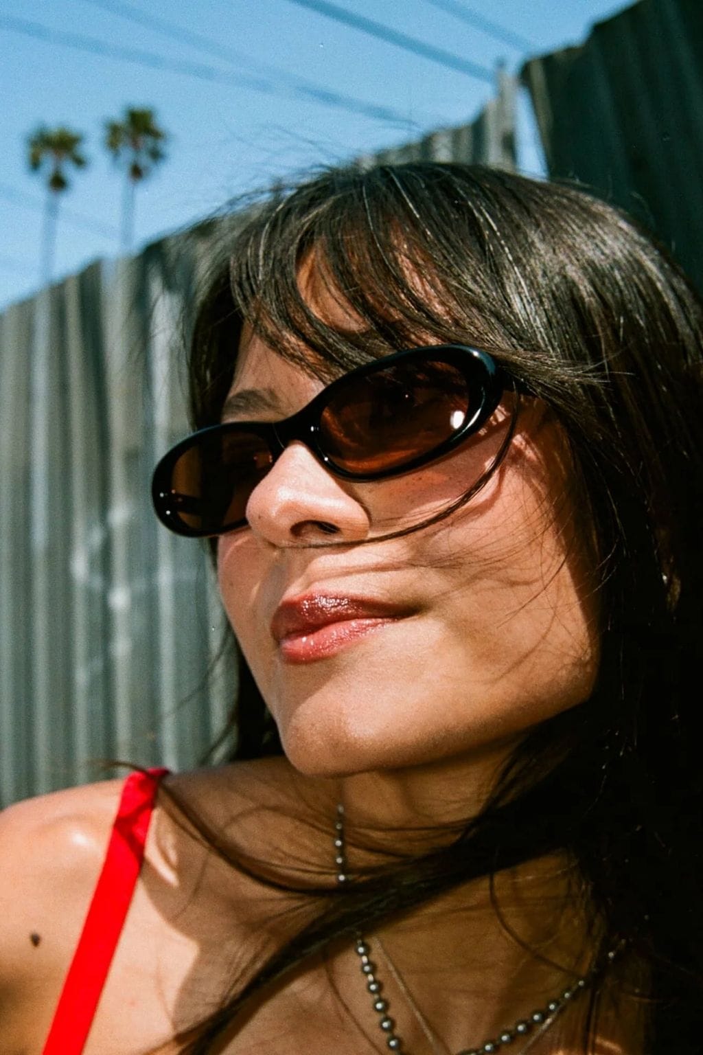 Black oval sunglasses with amber-tinted lenses worn by a person outdoors.