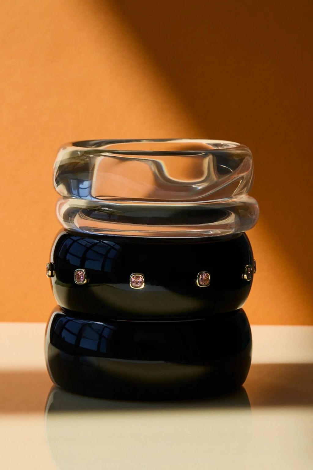 Clear lucite cuff stacked with black cuffs adorned with small crystal accents.
