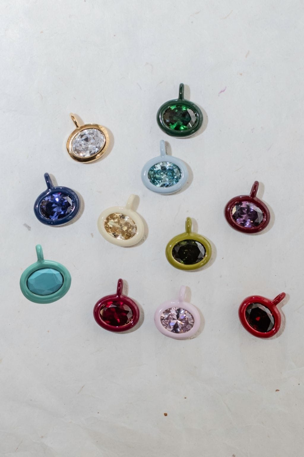 Collection of round birthstone charms in assorted colors including green, blue, purple, pink, and red with loop attachments.