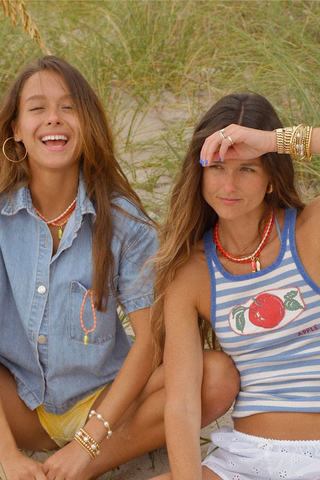 White beaded fish-shaped pendant necklace worn on woman's chest against denim shirt.