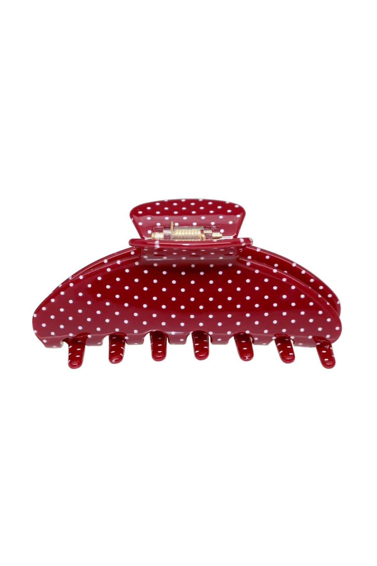 Red hair clip with white polka dot pattern and curved teeth along the bottom edge.