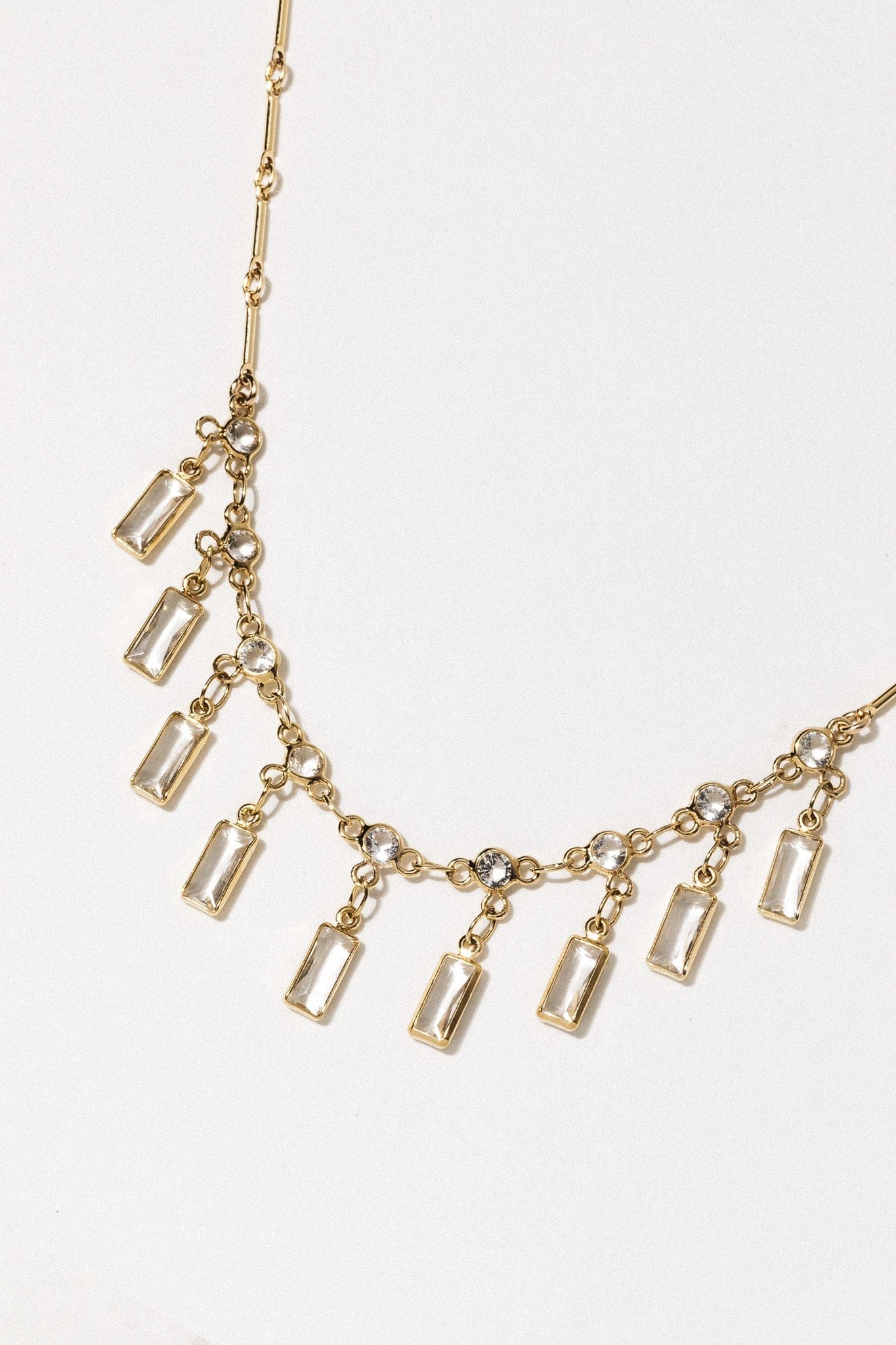 Gold-tone necklace with rectangular clear crystal pendants and round crystal accents on delicate chain.