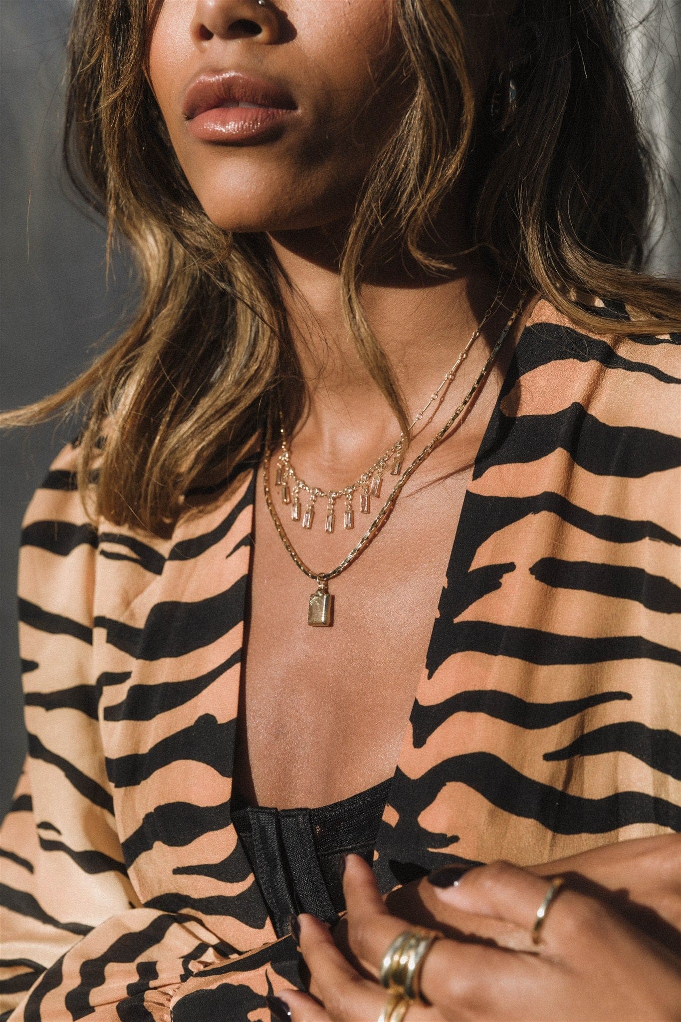Layered silver necklaces with cubic zirconia rectangular pendants worn on model's chest.