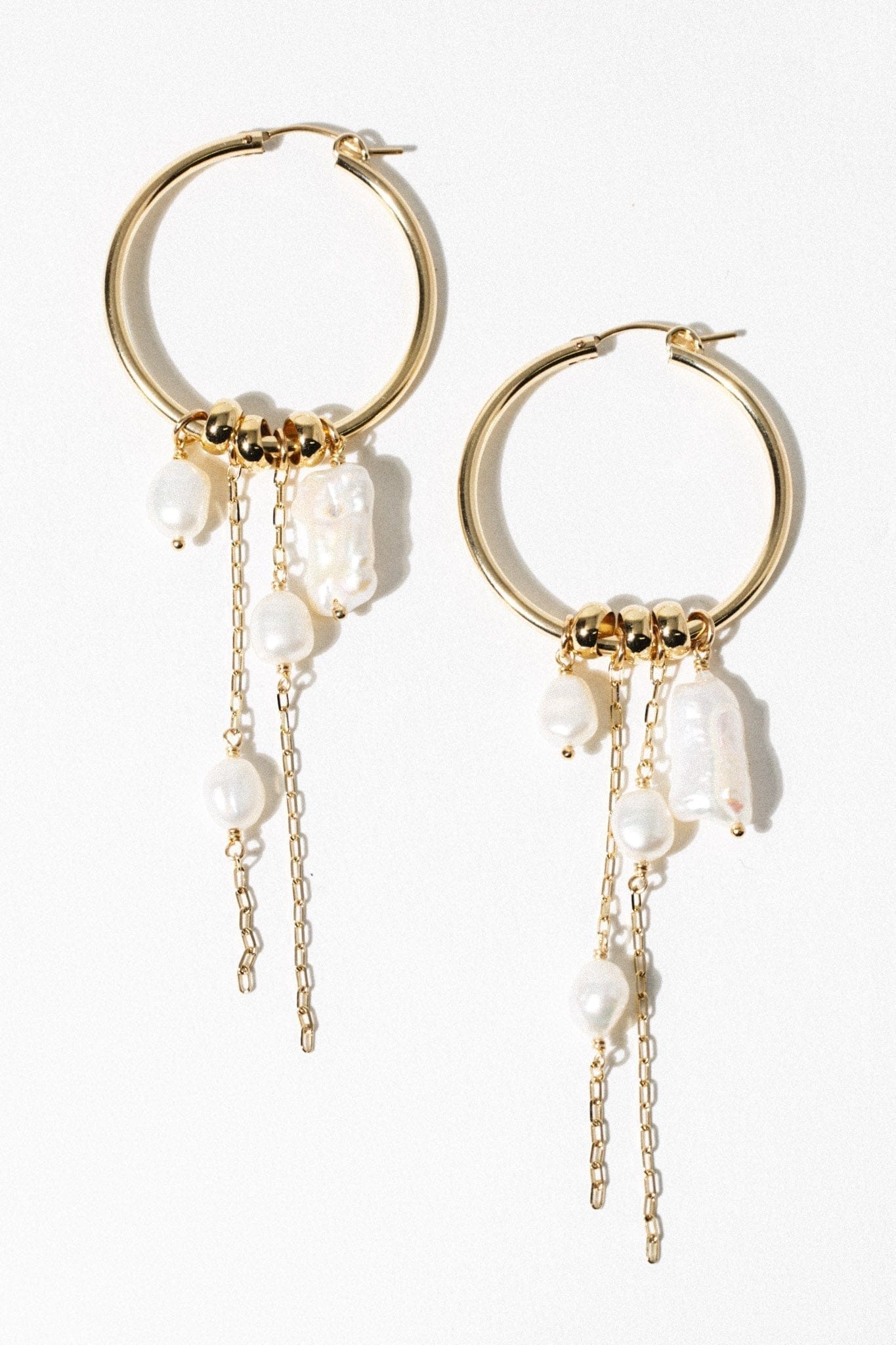 Pair of gold-tone hoop earrings with white pearl and rectangular stone charms hanging from gold chain strands.