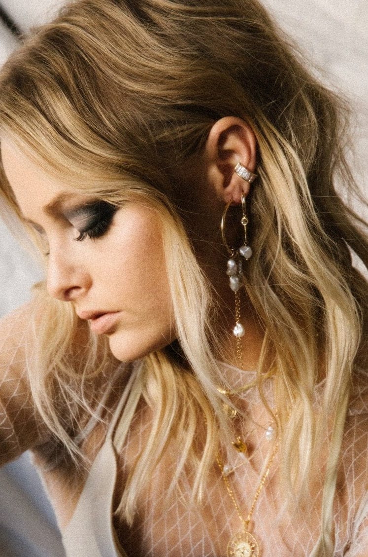 Pearl drop earrings with metal chain details worn on model with blonde hair.
