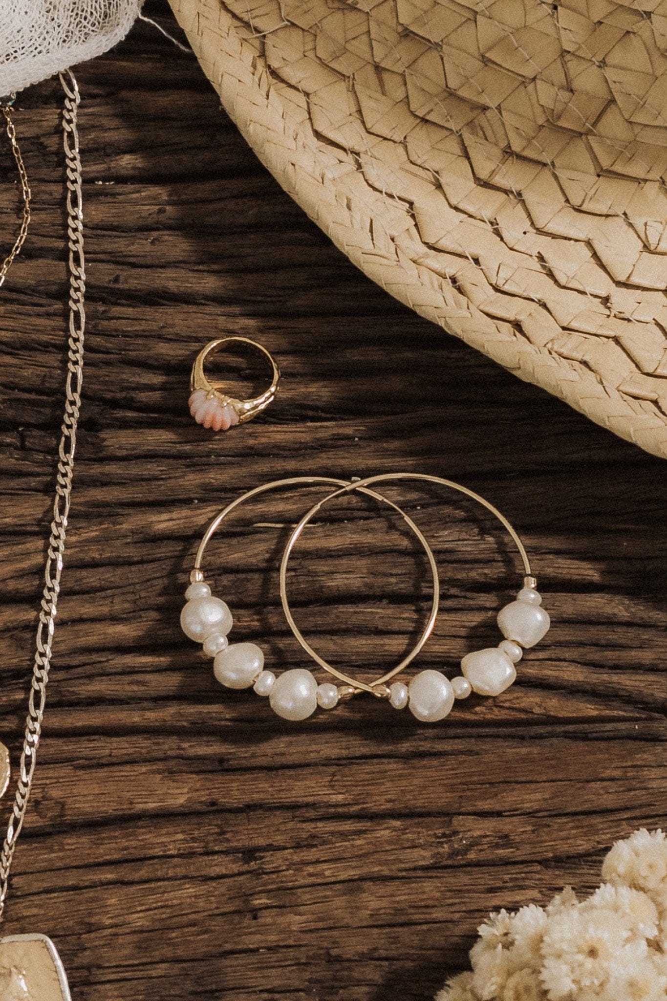 Gold hoop earrings with white pearl beads arranged around the band, displayed on dark wood surface.