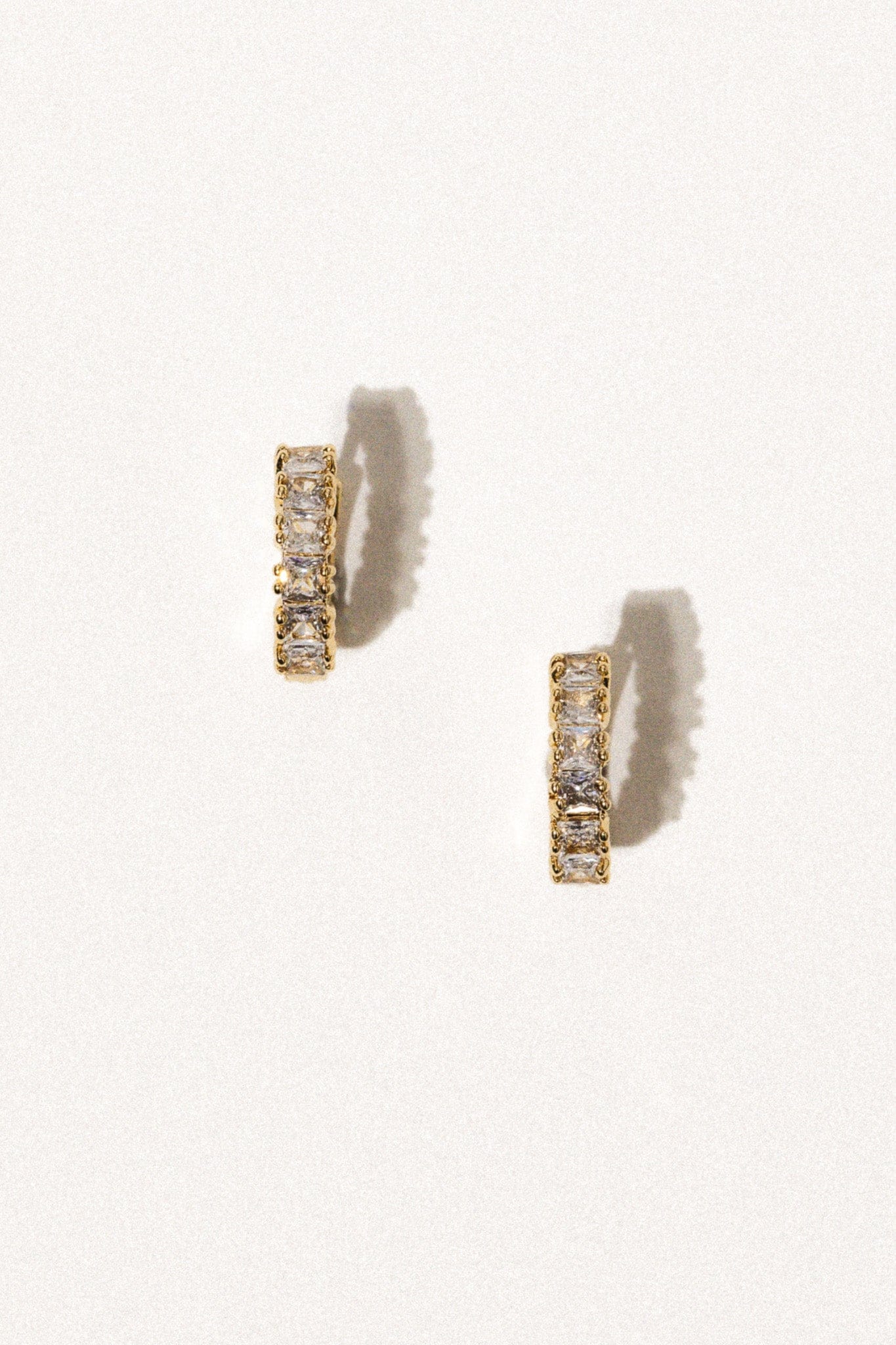 Pair of gold-tone huggie earrings with rectangular cubic zirconia stones set in rows.