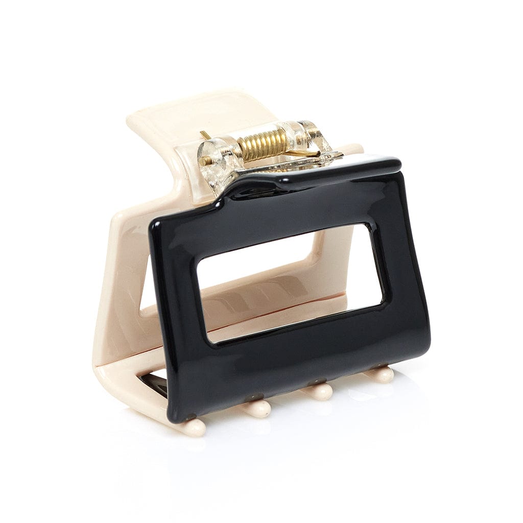 Rectangular hair clip with nude-colored back and black front panel, featuring a gold-toned spring mechanism.