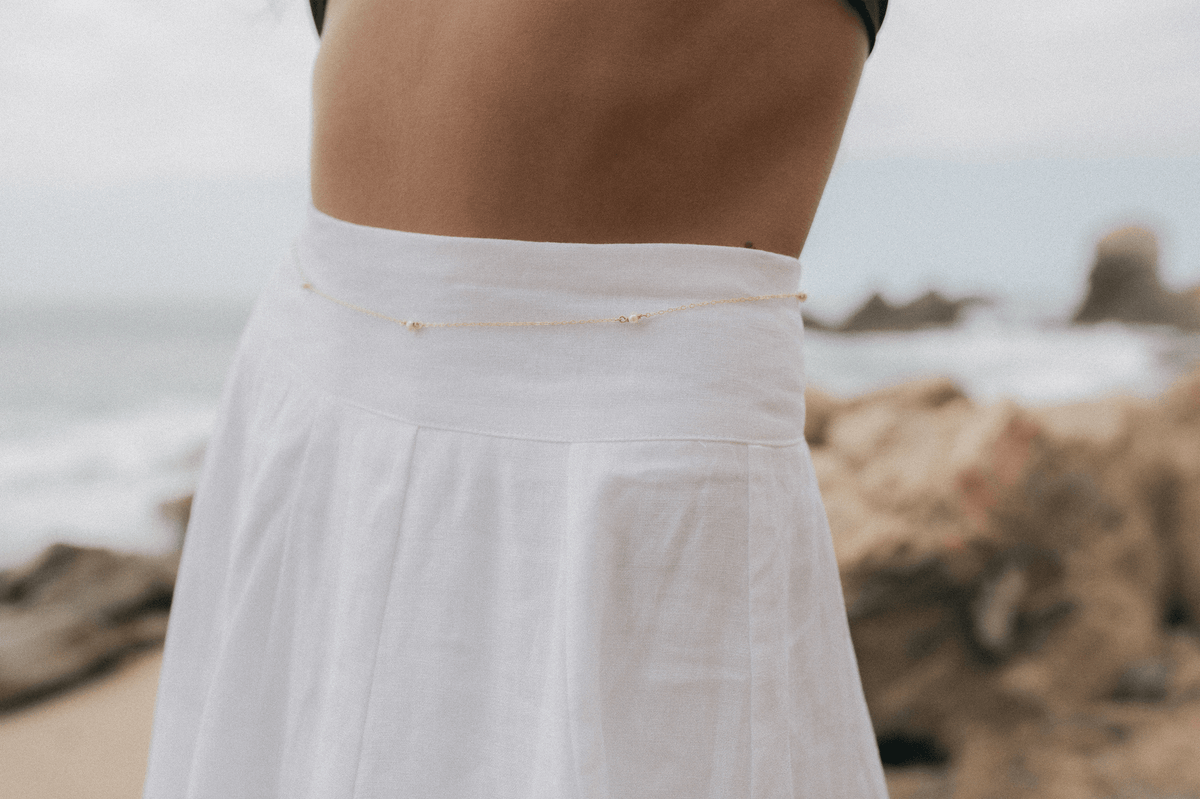 Gold-toned delicate chain with small pearl accents worn across the waist.