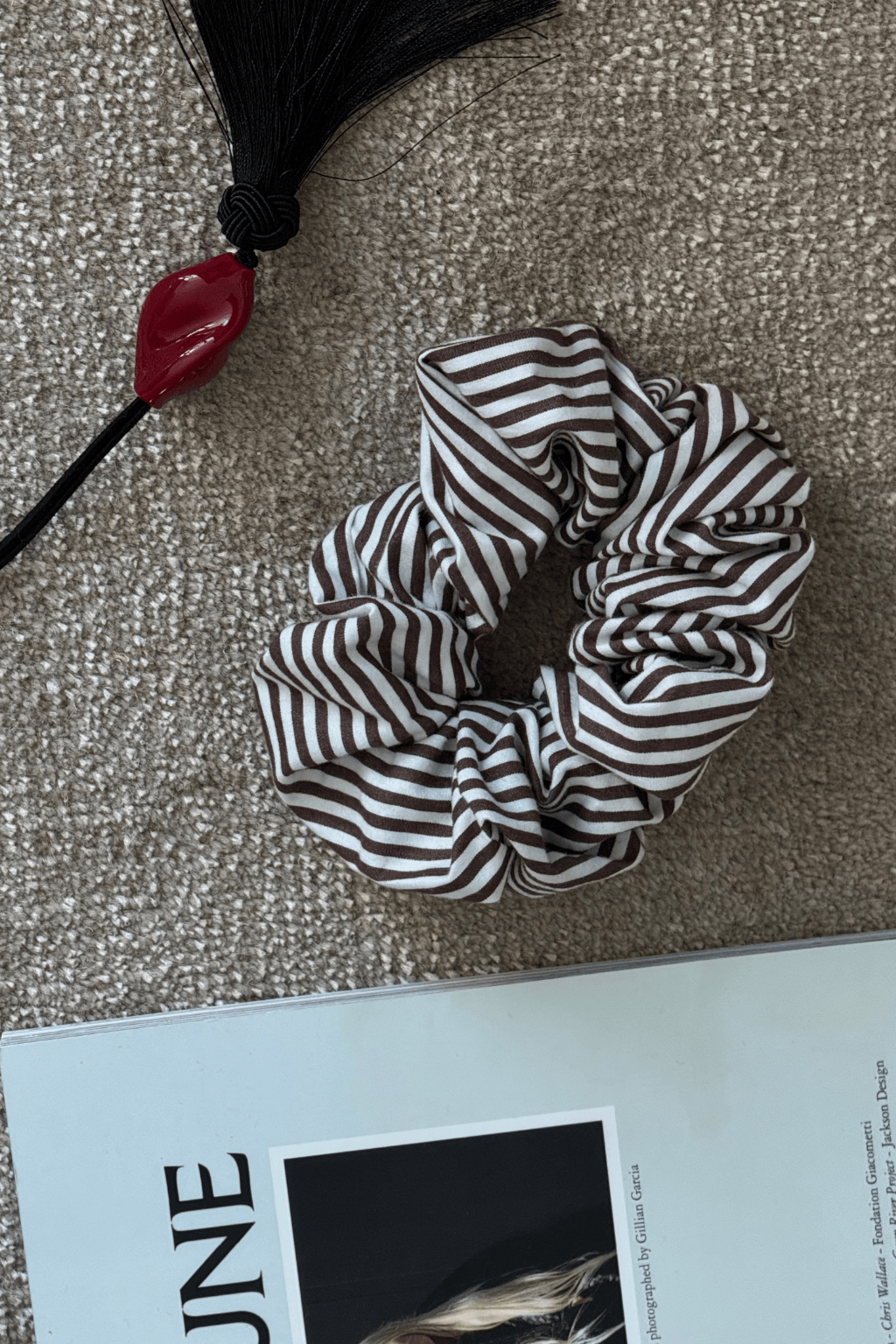 Black and white striped chunky scrunchie with black tassel and red bead accent.
