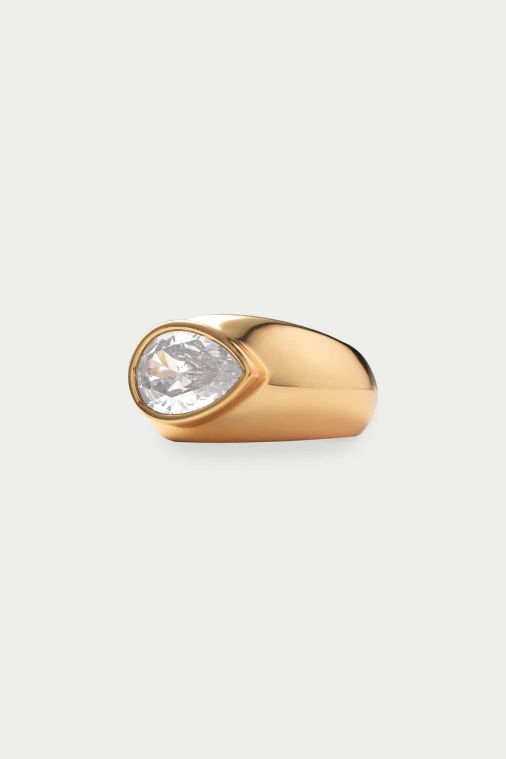 Gold-tone pinky ring with a teardrop-shaped clear crystal stone set on the side.