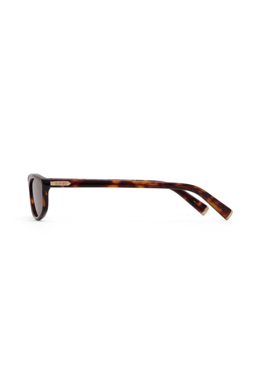 Tortoiseshell acetate sunglasses with dark lenses and gold metal temple detail shown from the side.