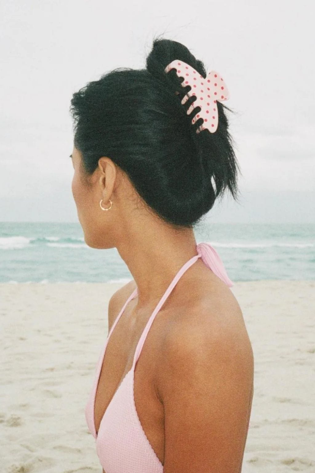 Blush pink polka dot hair clip securing dark hair in an updo style.
