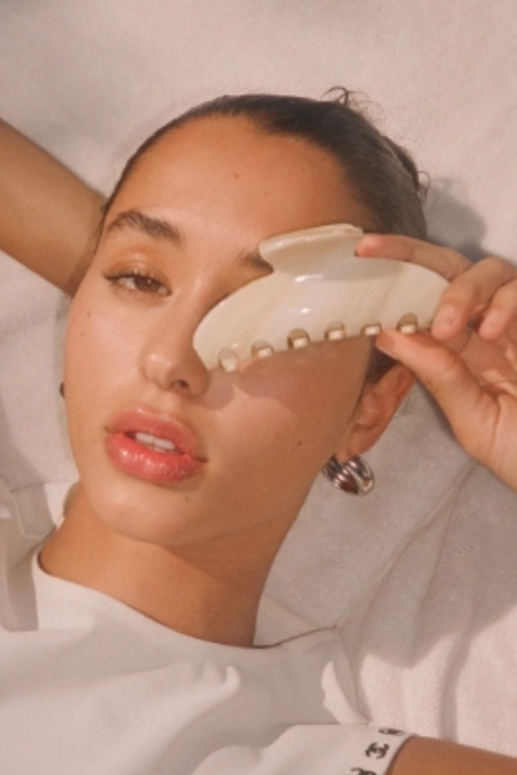 Large cream-colored claw hair clip with ridged teeth, worn in dark hair pulled back from face.