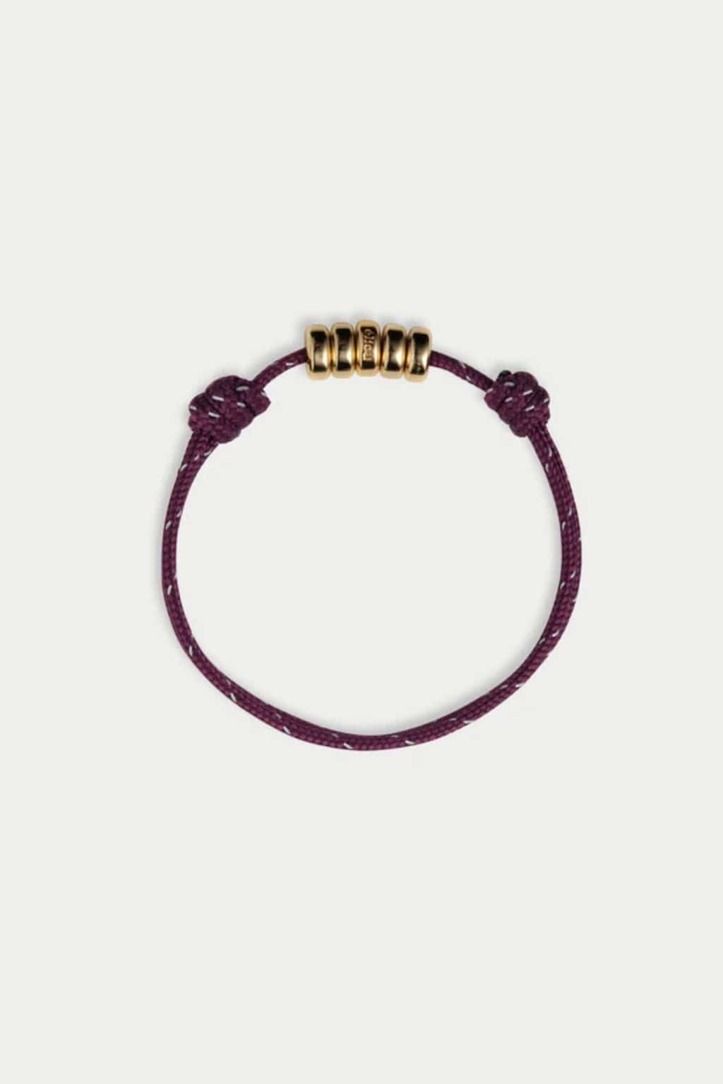 Purple braided cord bracelet with five gold-toned cylindrical beads and knotted ends.