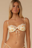 Cream bikini top with orange cherry print, ruched cups, tie front closure, and adjustable straps.