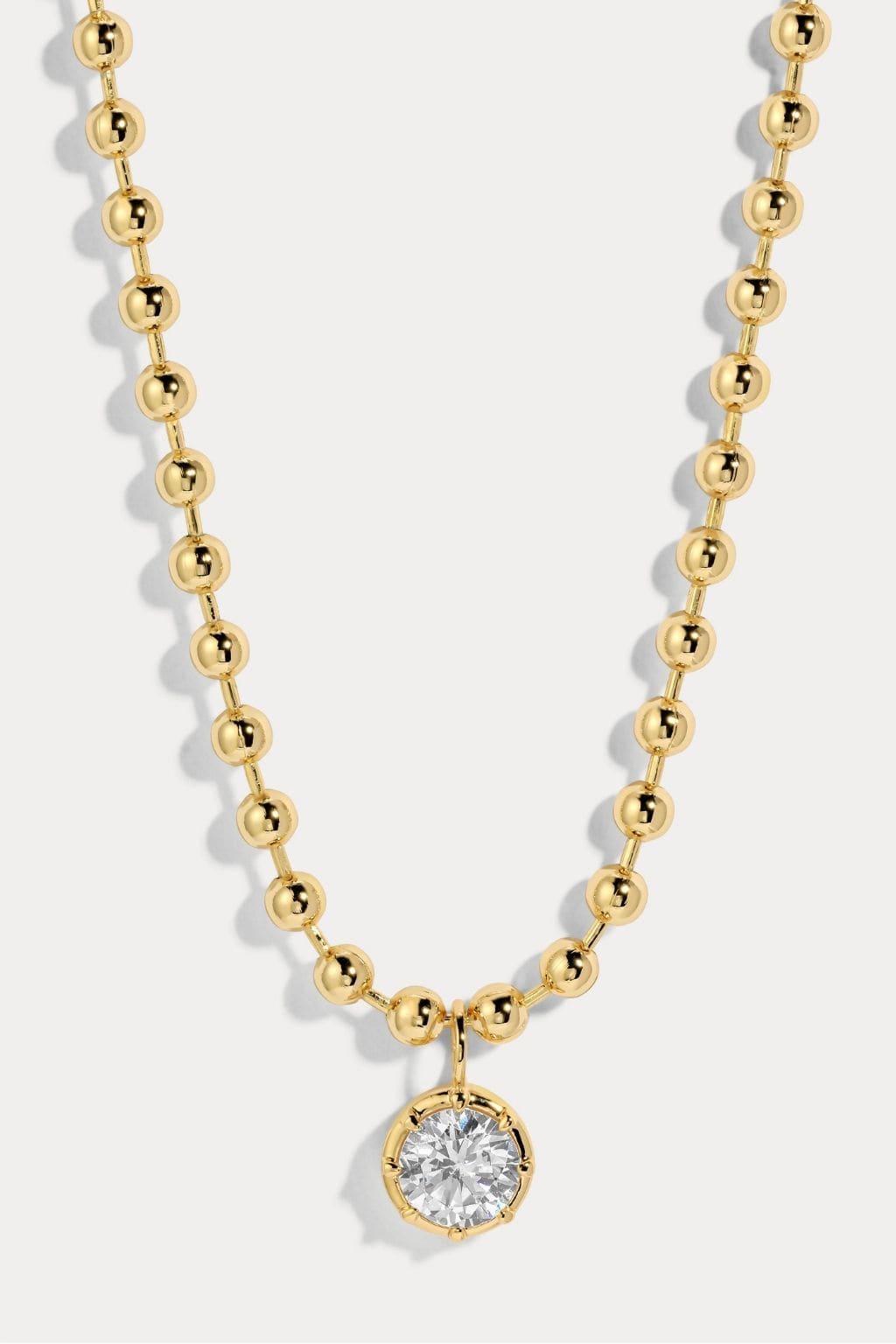 Gold ball chain necklace with round crystal pendant drop.