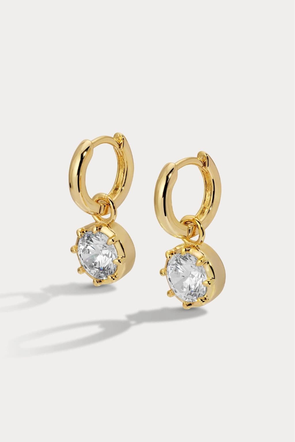 Pair of gold-plated hoop earrings with round cubic zirconia stone drops.