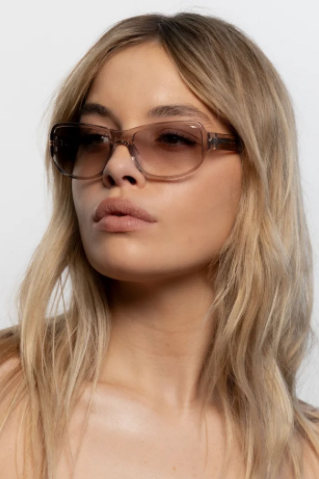 Mink-colored oversized square sunglasses with gradient lenses worn by a model with long blonde hair.