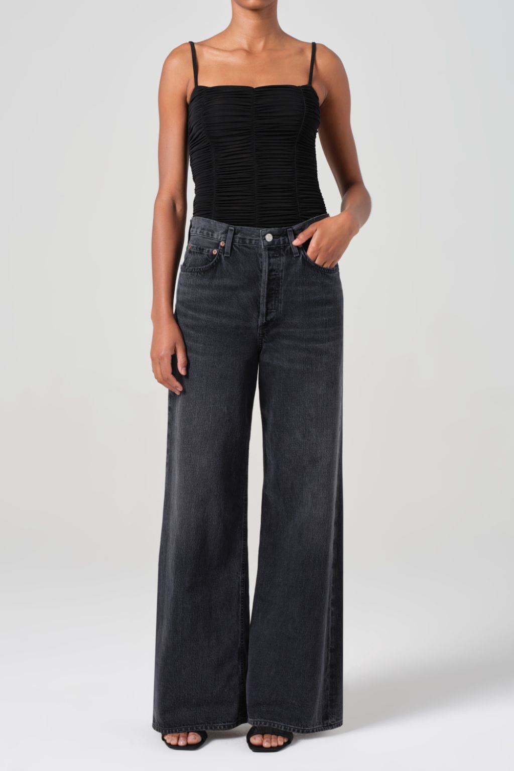 Woman wearing black ruched camisole top and dark wash wide-leg denim jeans with no cuff.