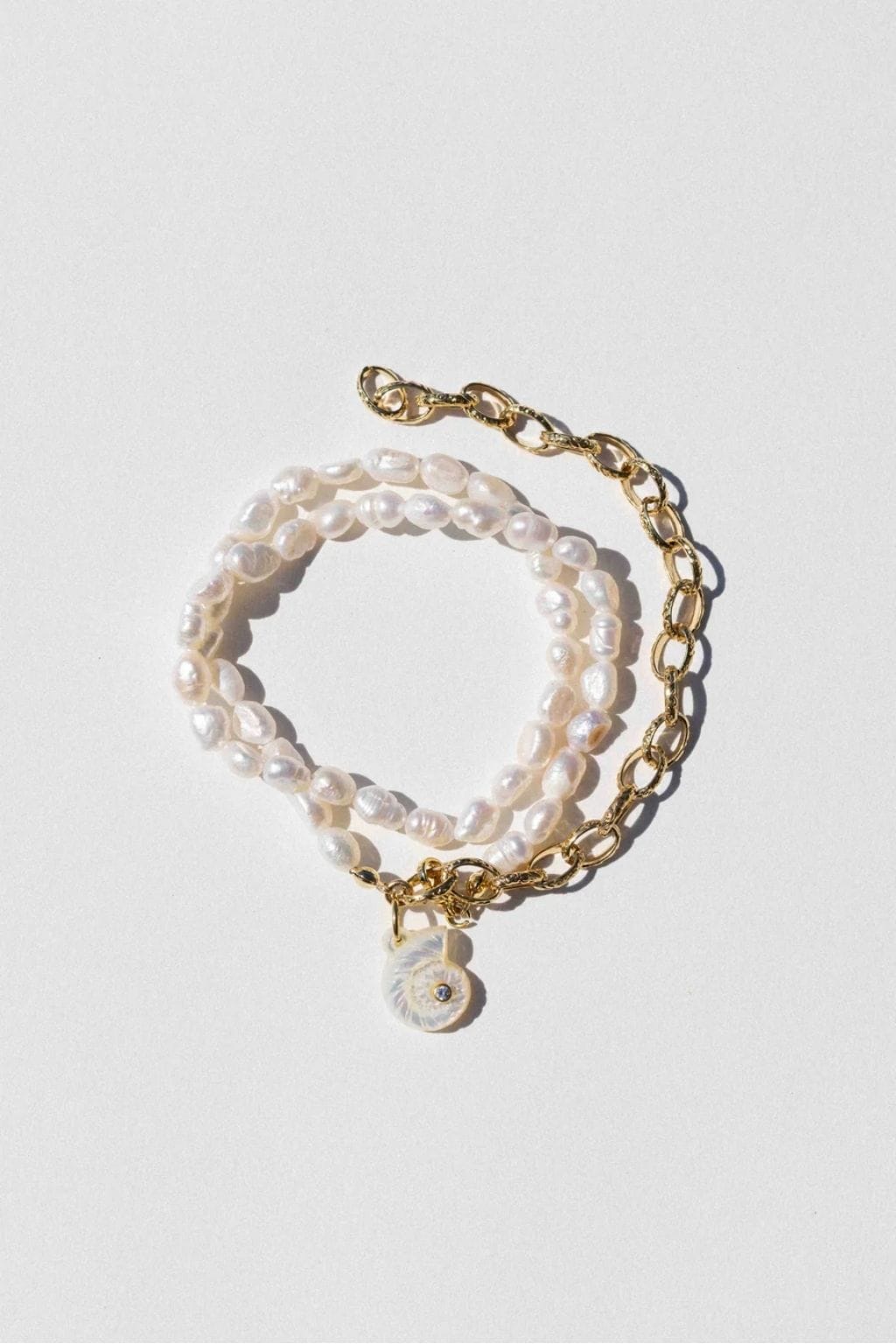 Gold-tone anklet with two strands of cream pearls, gold chain link section, and small pearl shell charm pendant.