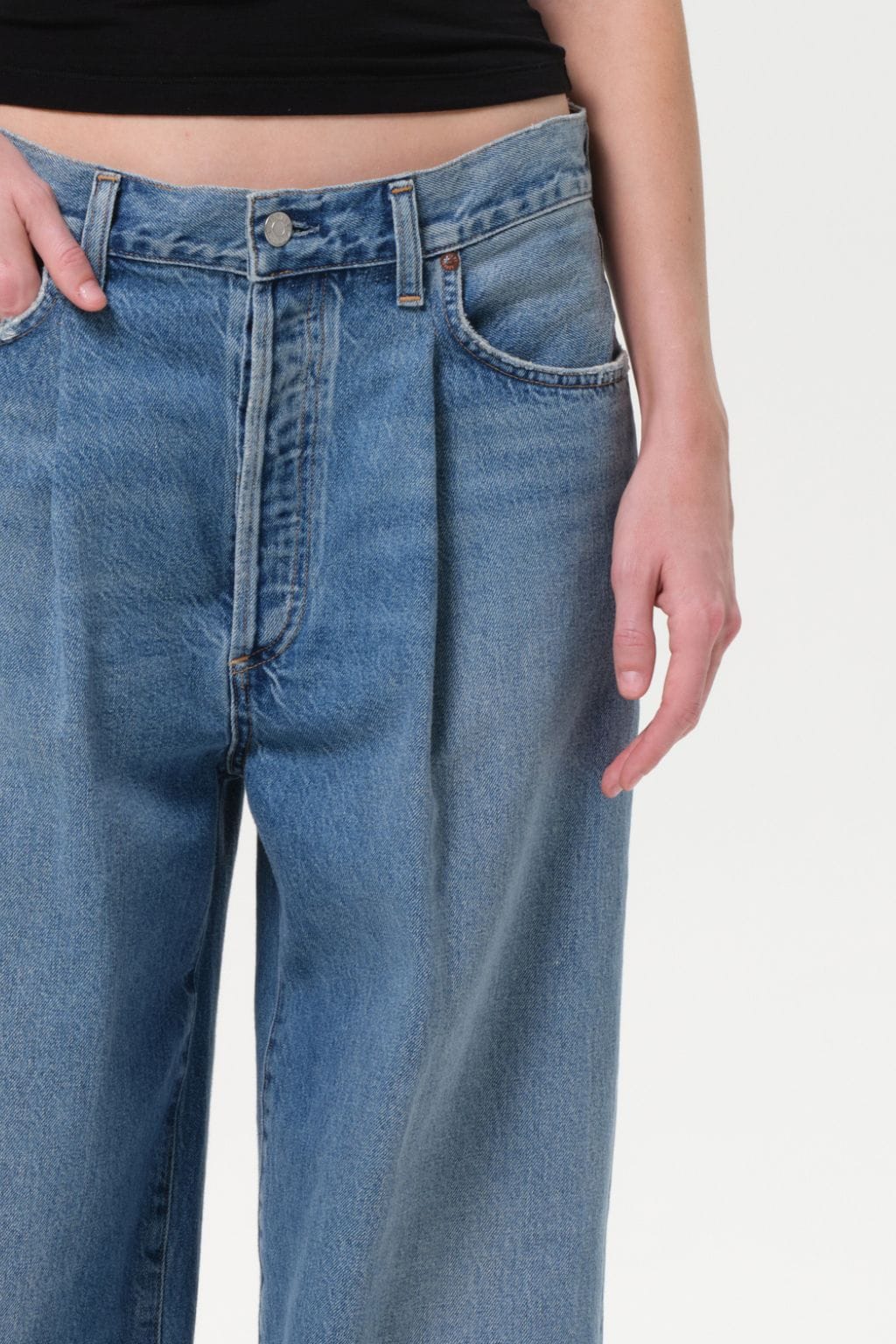 Blue denim baggy jeans with pleated front detail and button closure at waist.